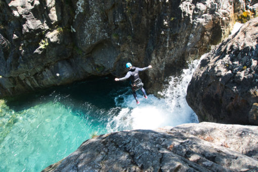 Cette image montre un homme sautant dans une rivière