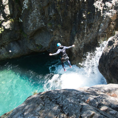 Cette image montre un homme sautant dans une rivière